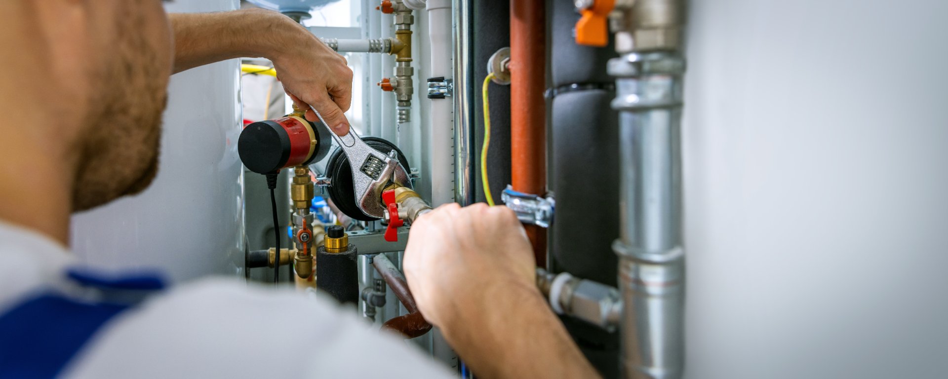 Plumber tightening a fitting on a pressurized supply line during a leak repair